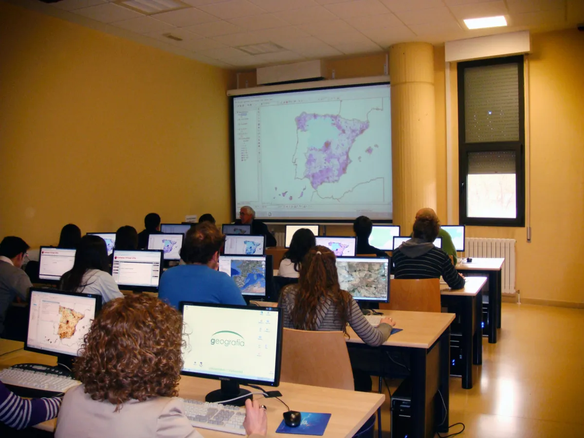 Alumnos en un aula de informática del Departamento de Geografía siguiendo una clase de SIG proyectada en pantalla